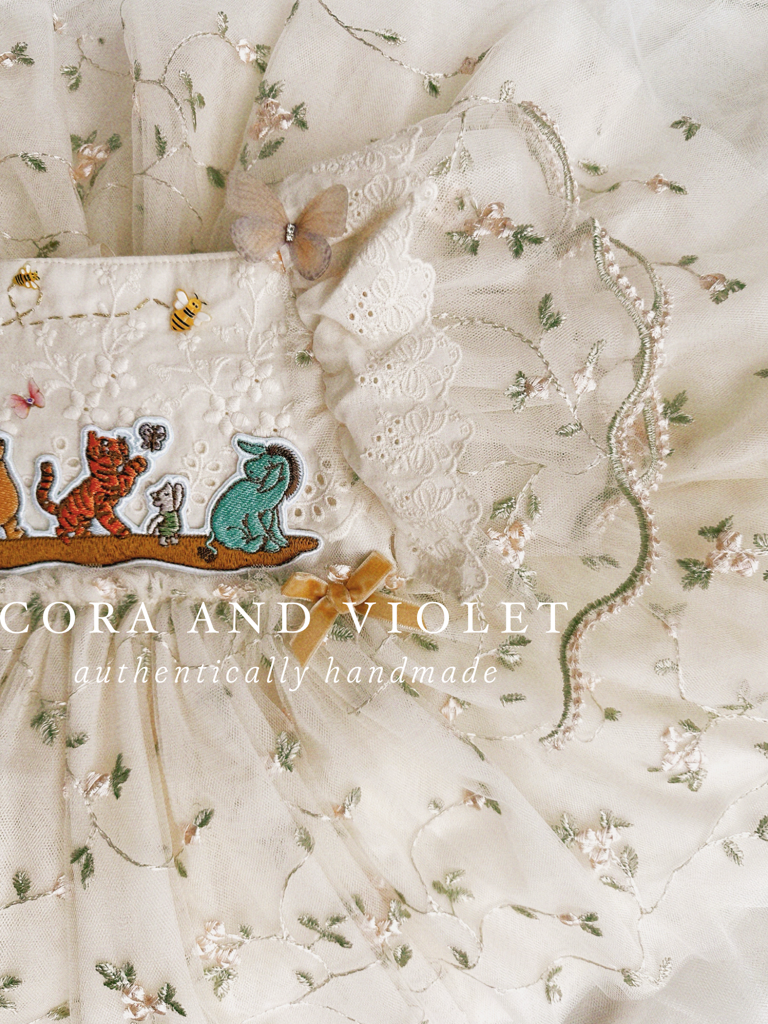 closue up shot artisan-stitched rosebuds and hand-applied butterflies on a luxury classic pooh milestone gown.
