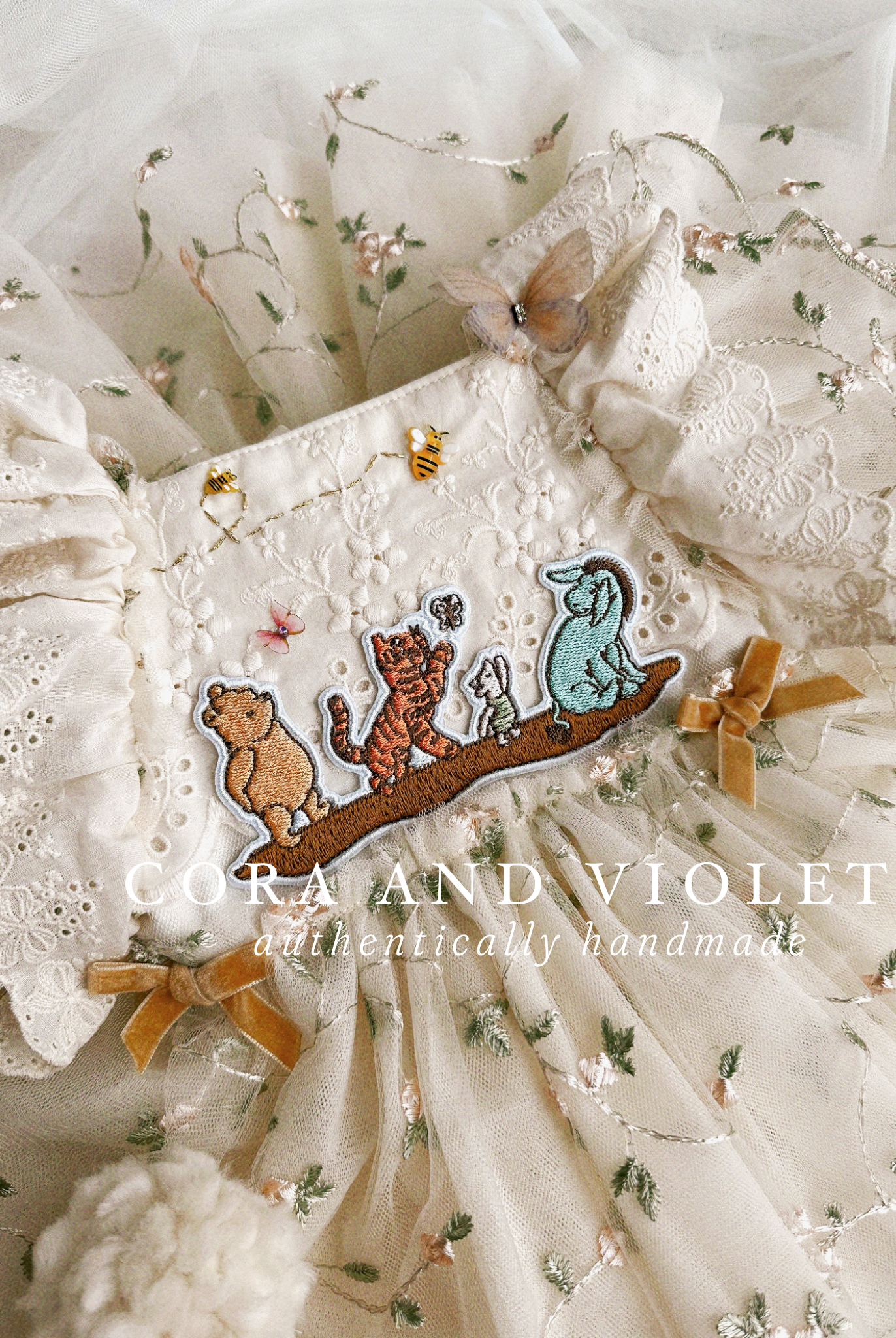 Close-up of artisan-stitched rosebuds and hand-applied butterflies on a luxury classic pooh milestone gown.