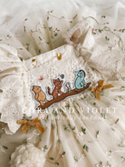 Close-up of artisan-stitched rosebuds and hand-applied butterflies on a luxury classic pooh milestone gown.