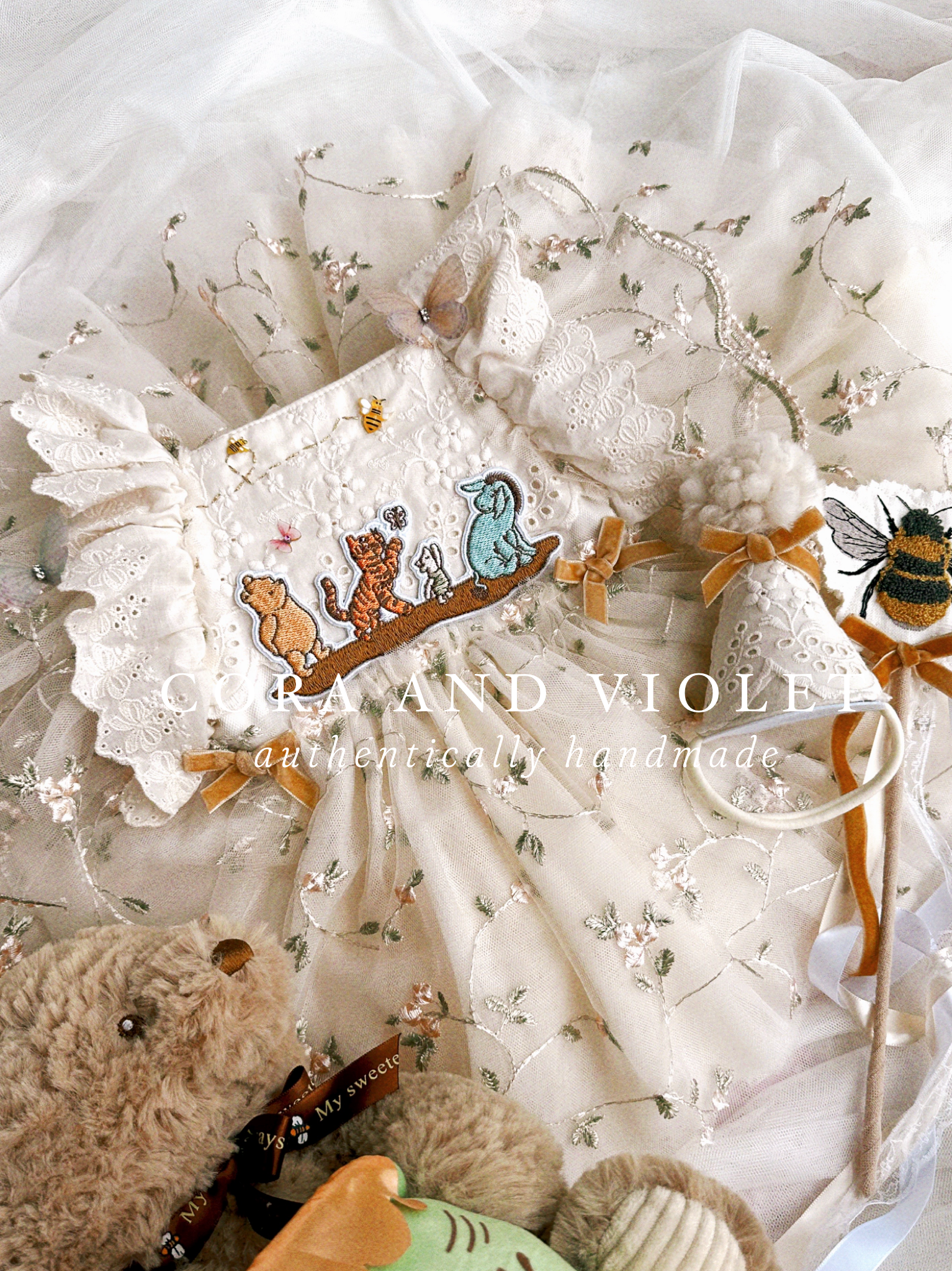 The Winnie Heirloom by Cora and Violet, a handmade Winnie the Pooh inspired birthday artisan-stitched rosebuds and hand-applied butterflies on a luxury classic pooh milestone gown.