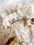 The Winnie Heirloom by Cora and Violet, a handmade Winnie the Pooh inspired birthday artisan-stitched rosebuds and hand-applied butterflies on a luxury classic pooh milestone gown.